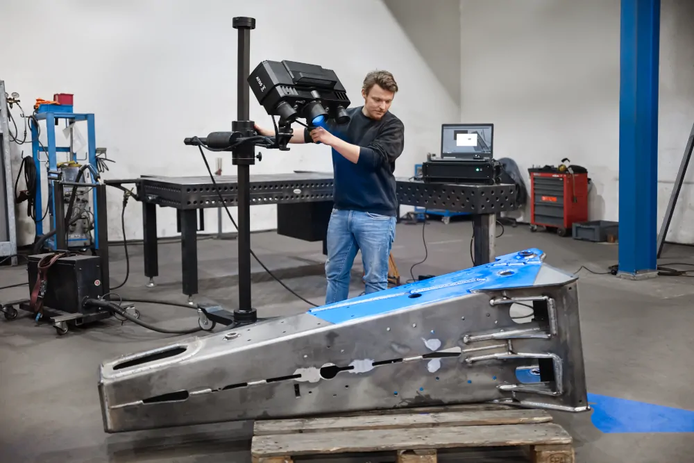 A man performing 3D Metrology on a large metal part with the GOM Atos scanner