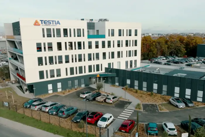 Aerial view of Testia headquarters, a five-story building with a dozen parking lots in front